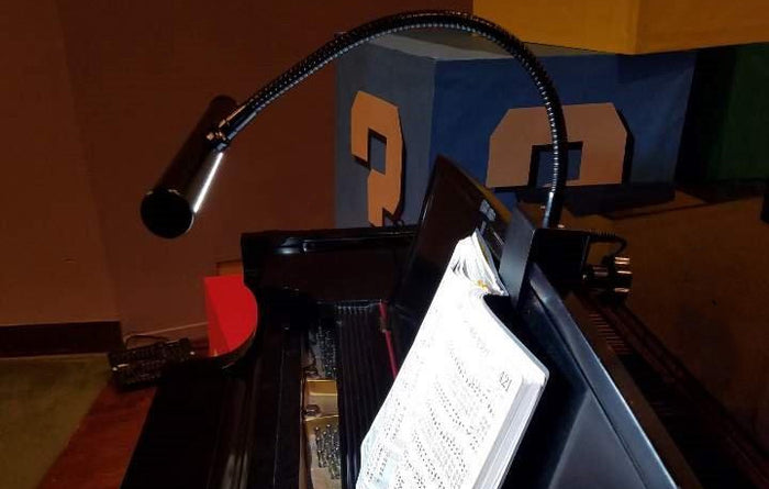 piano with a black led piano lamp on sheet music rack