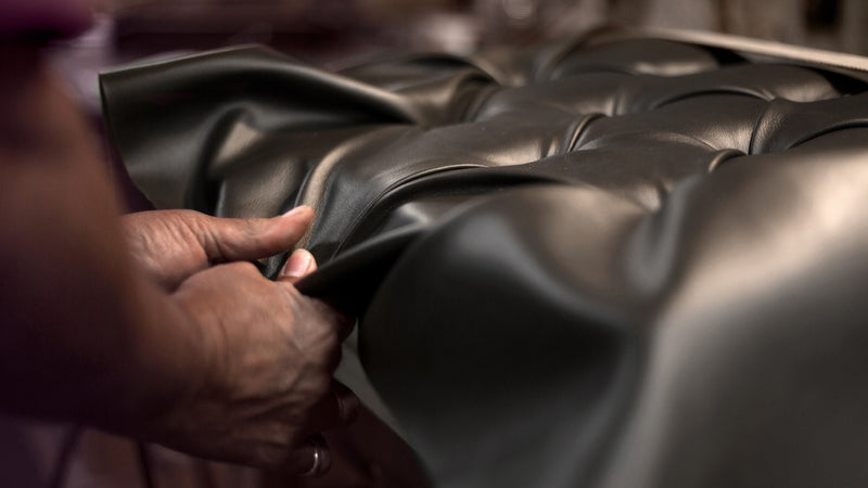 Artisan smoothing premium leather on an American-made piano bench